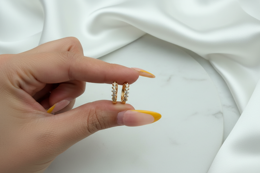 Natalia Hoop CZ huggie earrings held in hand on white satin marble