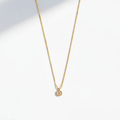 Gold sunflower pendant necklace with straight chain on flat surface