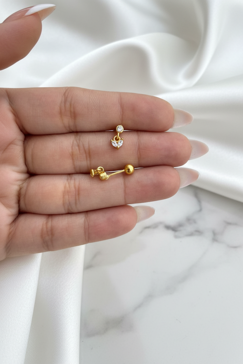 Gold crystal heart drop stud earrings showing front and ball-back closure on white satin marble background