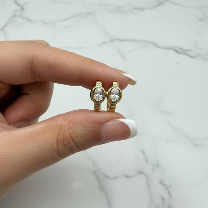 Victoria Huggie oval CZ earrings held with French nude nails on white marble