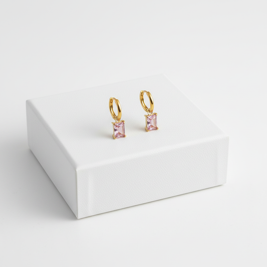 Pink Drop Huggies displayed on white jewelry box