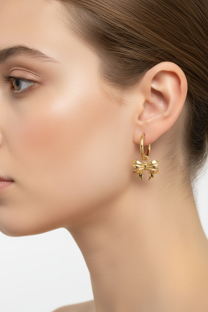 Gold bow earrings worn on ear