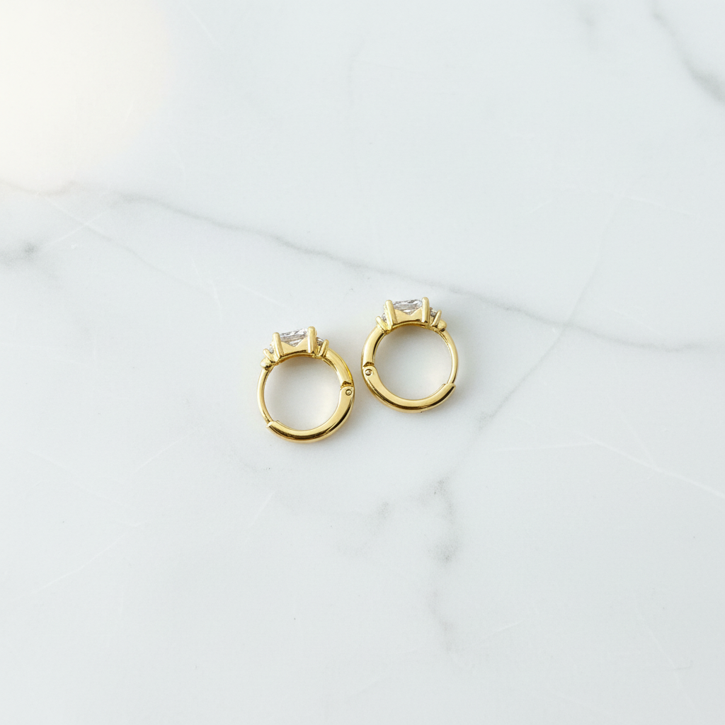 Dante Huggies gold CZ earrings flat lay on white marble