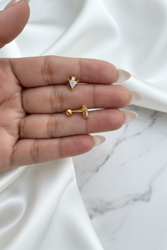 Gold crystal triangle arrow stud earrings showing front and ball-back closure on white satin marble background